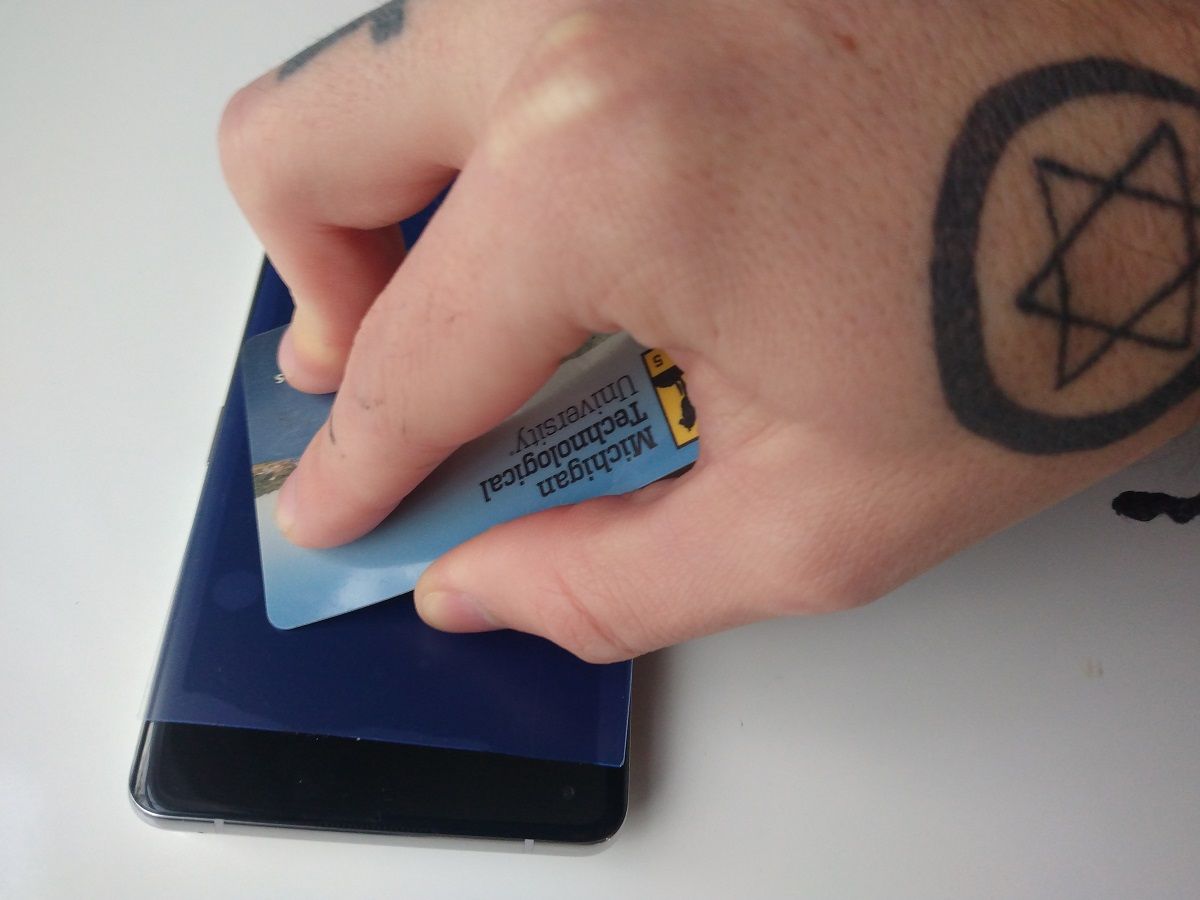 Пластиковая карта выталкивает пузырьки под плёнкой на смартфоне