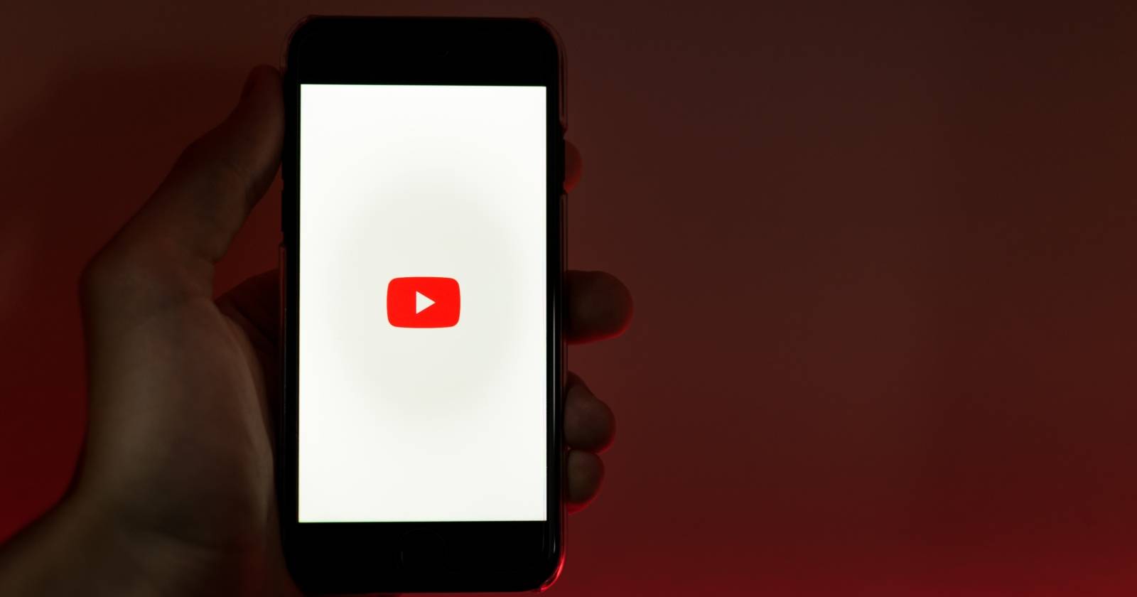 Человек держит смартфон с логотипом YouTube