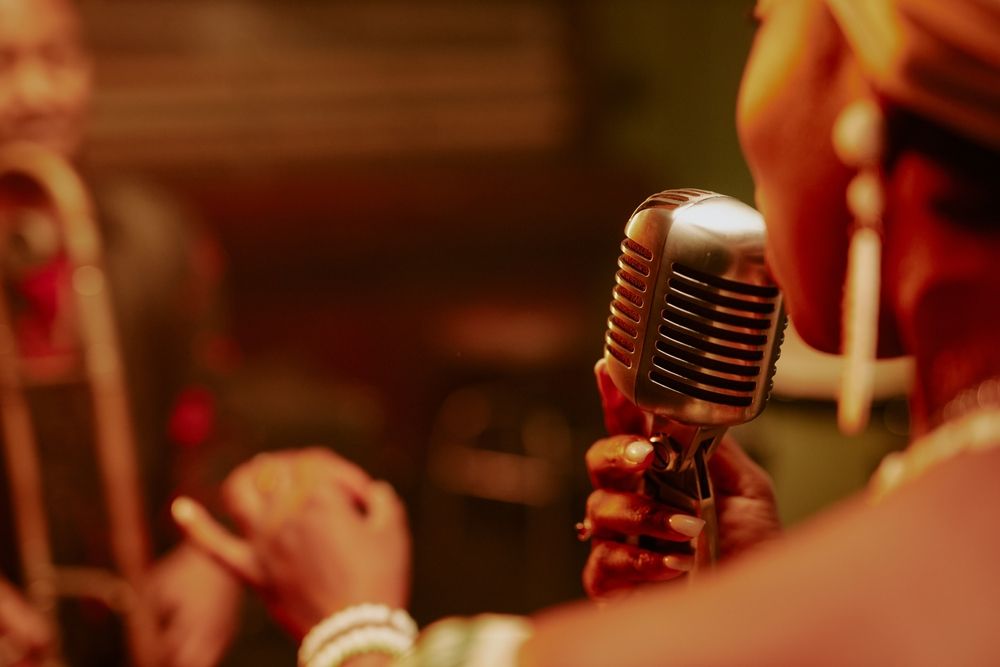 Вид сзади на женщину, поющую в винтажный микрофон.
