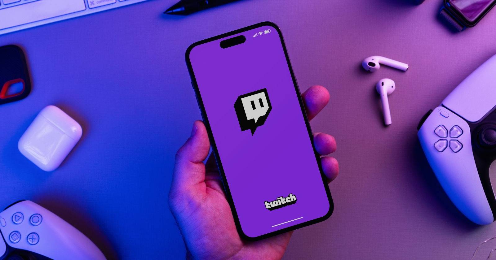 Мужчина держит смартфон iPhone 14 Pro с открытым приложением Twitch