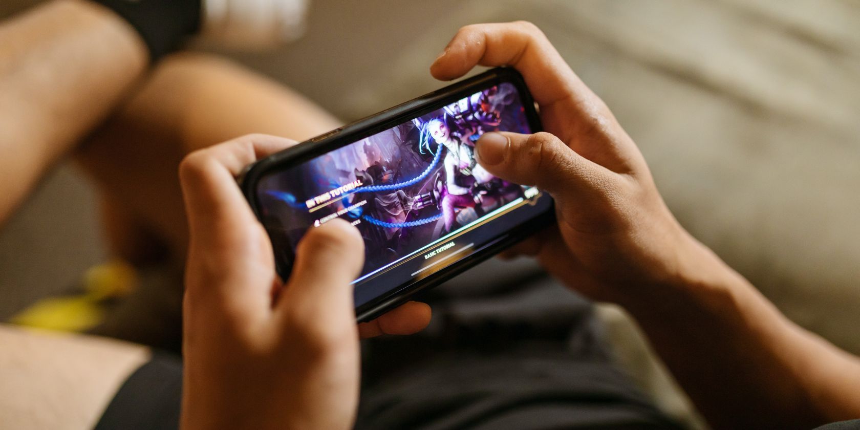 Человек играет в мобильную игру на диване