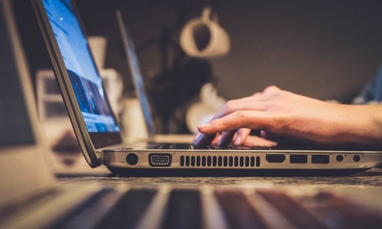 Крупный план: человек печатает на серебристом ноутбуке за рабочим столом