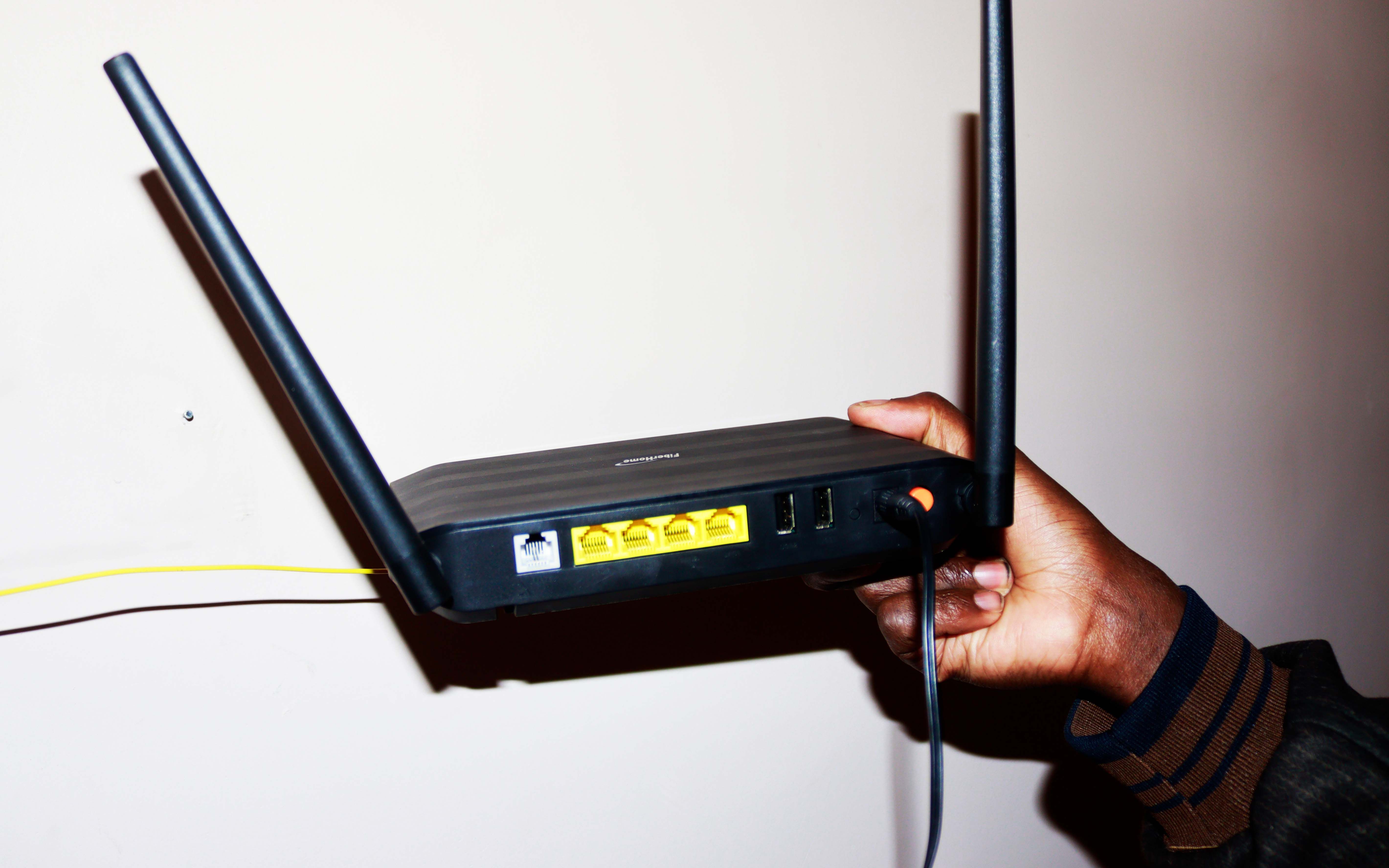 Рука держит чёрный роутер