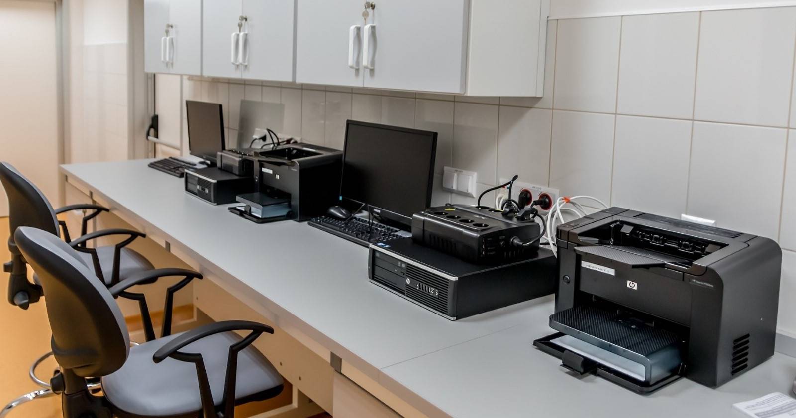 Несколько офисных компьютеров и принтеров на рабочих местах