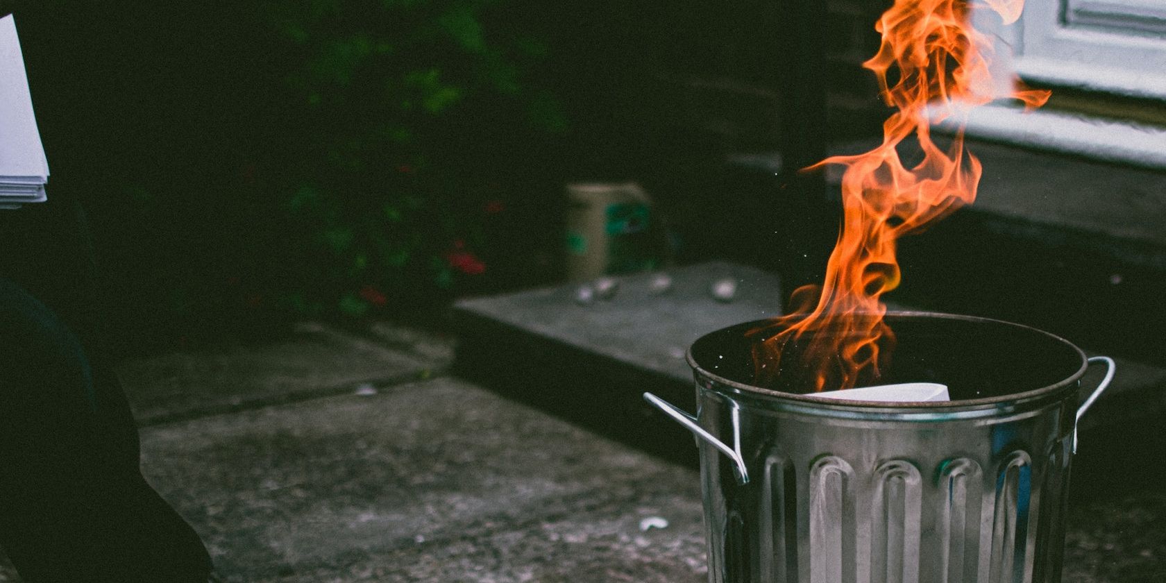 Человек бросает бумагу в горящую корзину