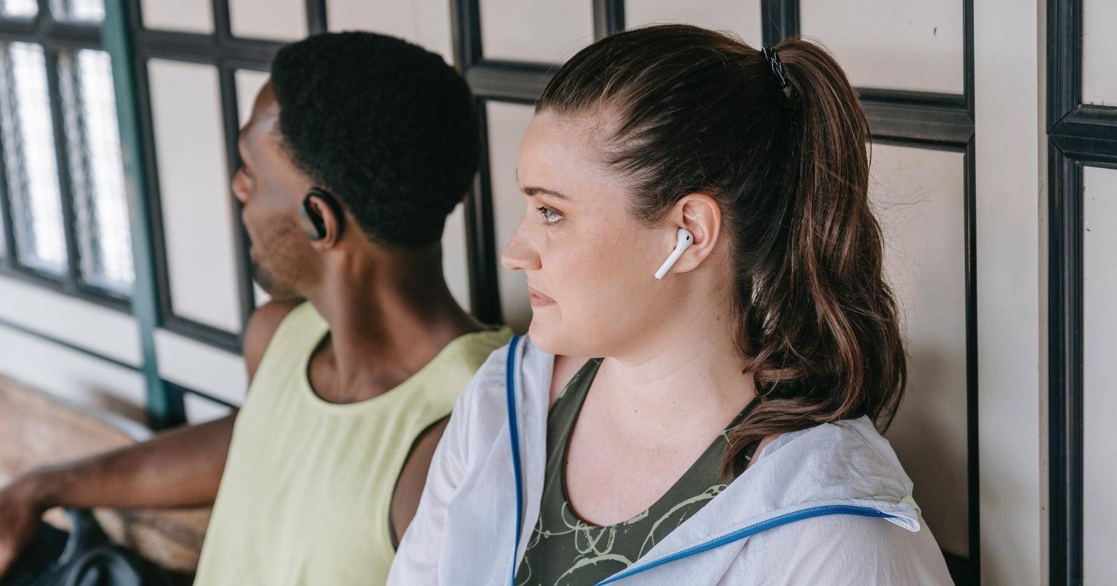 Двое людей в наушниках AirPods и ещё один в полноразмерных наушниках тренируются и слушают музыку