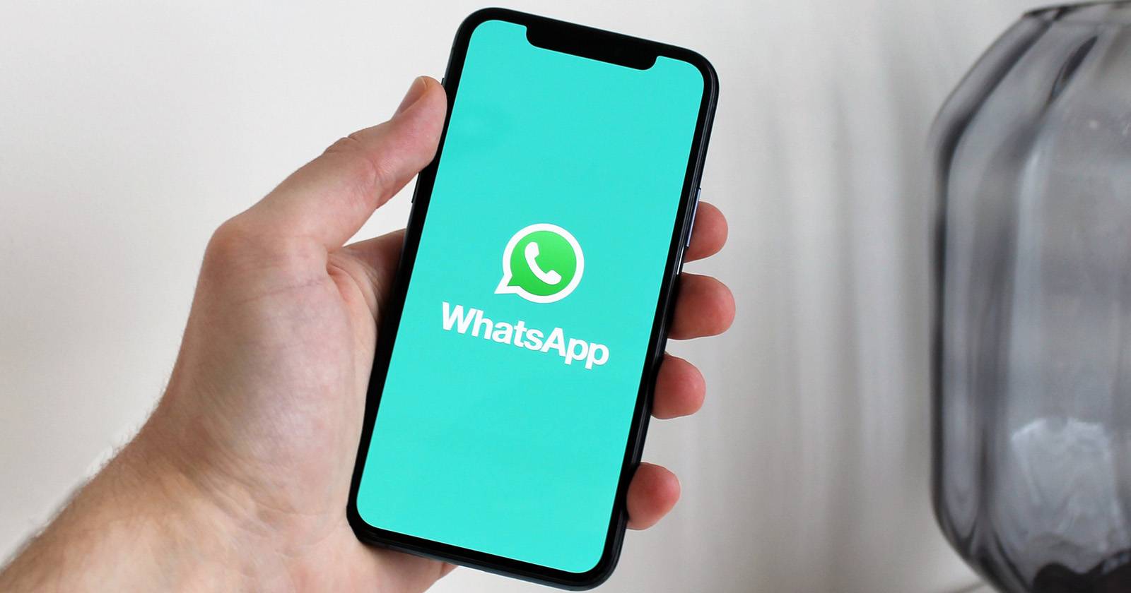 Человек держит телефон с открытым WhatsApp