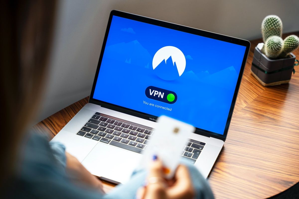 Человек держит банковскую карту, ноутбук подключён к VPN
