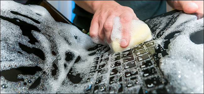 Человек протирает ноутбук спиртовой салфеткой, чтобы подготовить его к продаже