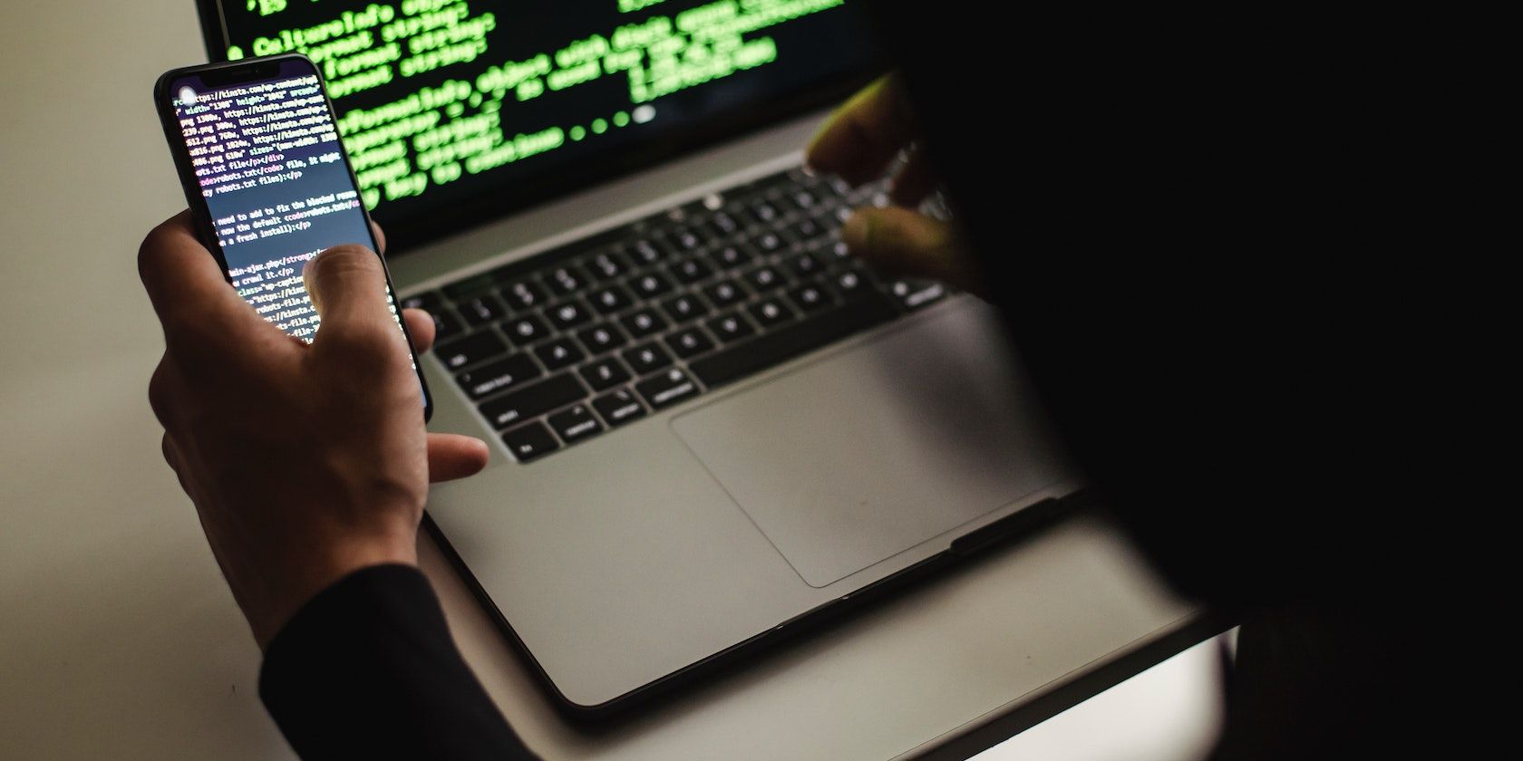 Разработчик пишет код на ноутбуке и телефоне