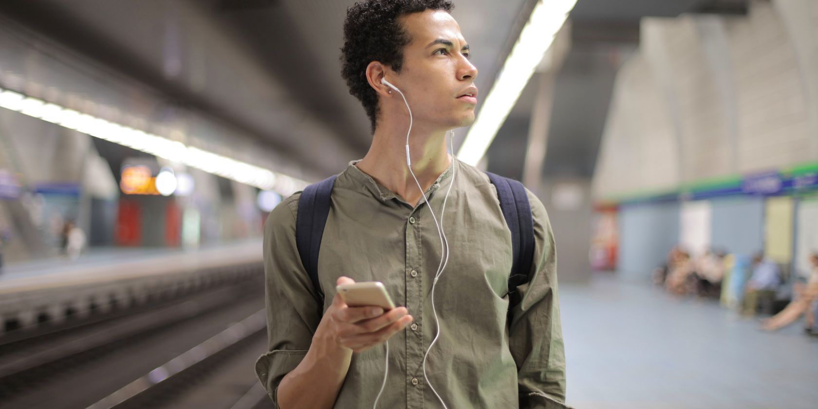 person on their phone wearing earbuds in a subway
