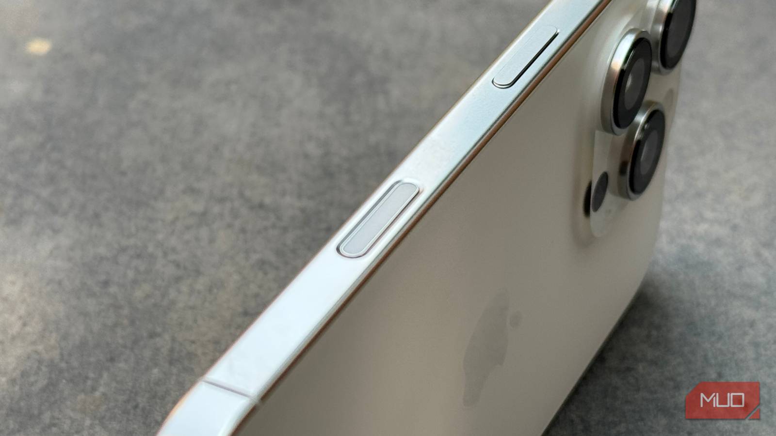 iPhone 16 Pro на каменной плите, крупный план правого края с кнопкой управления камерой