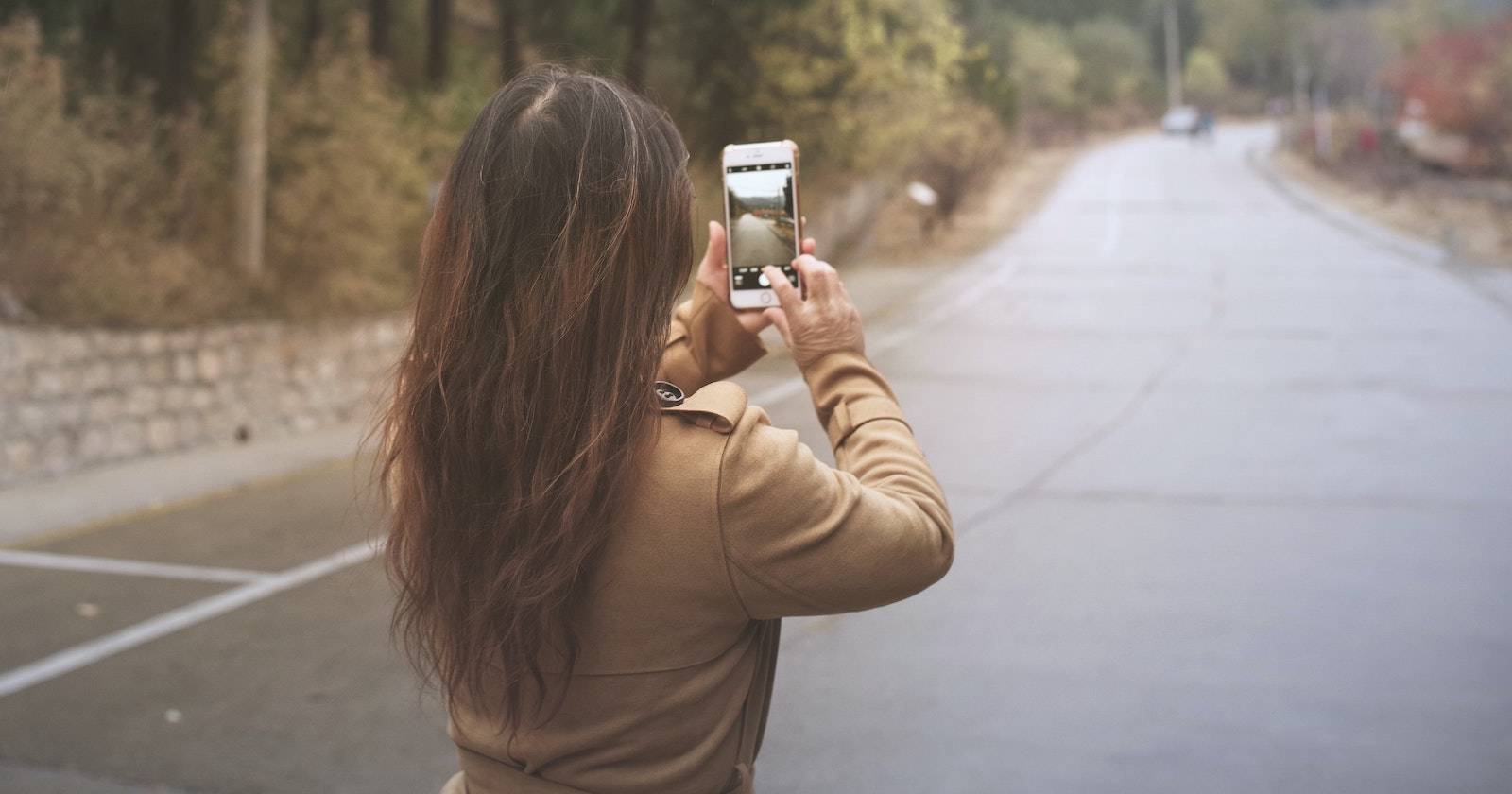 девушка фотографирует дорогу на iPhone