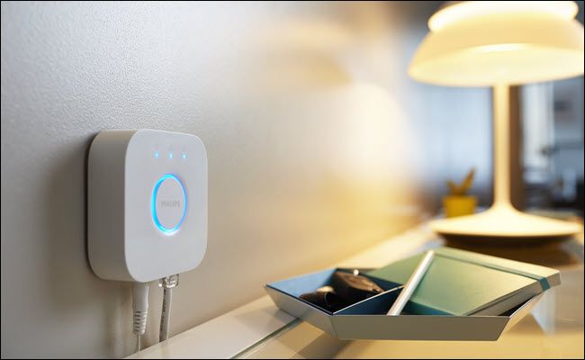 Хаб Philips Hue рядом с настольной лампой на туалетном столике.