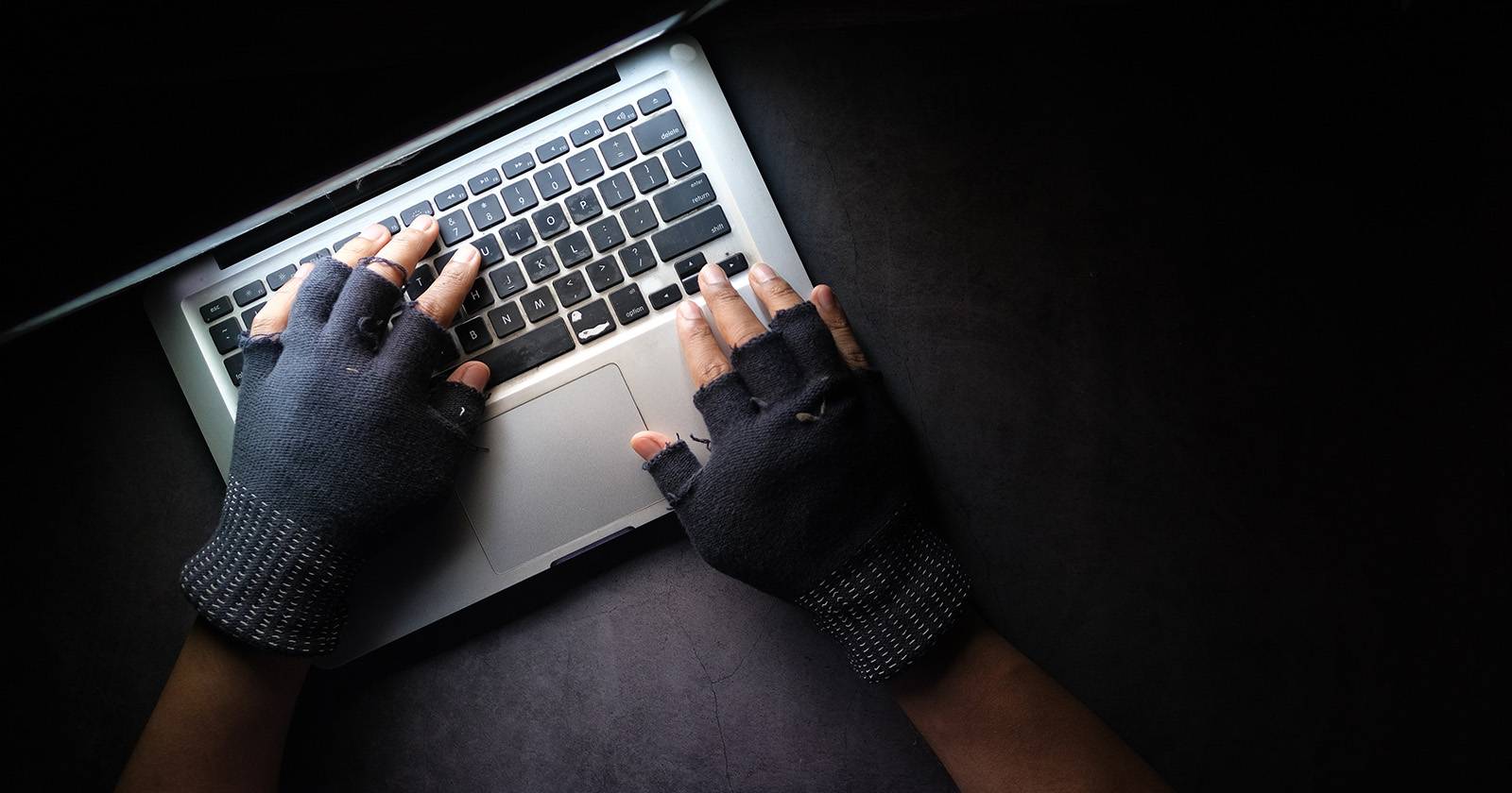 Человек в перчатках работает на MacBook