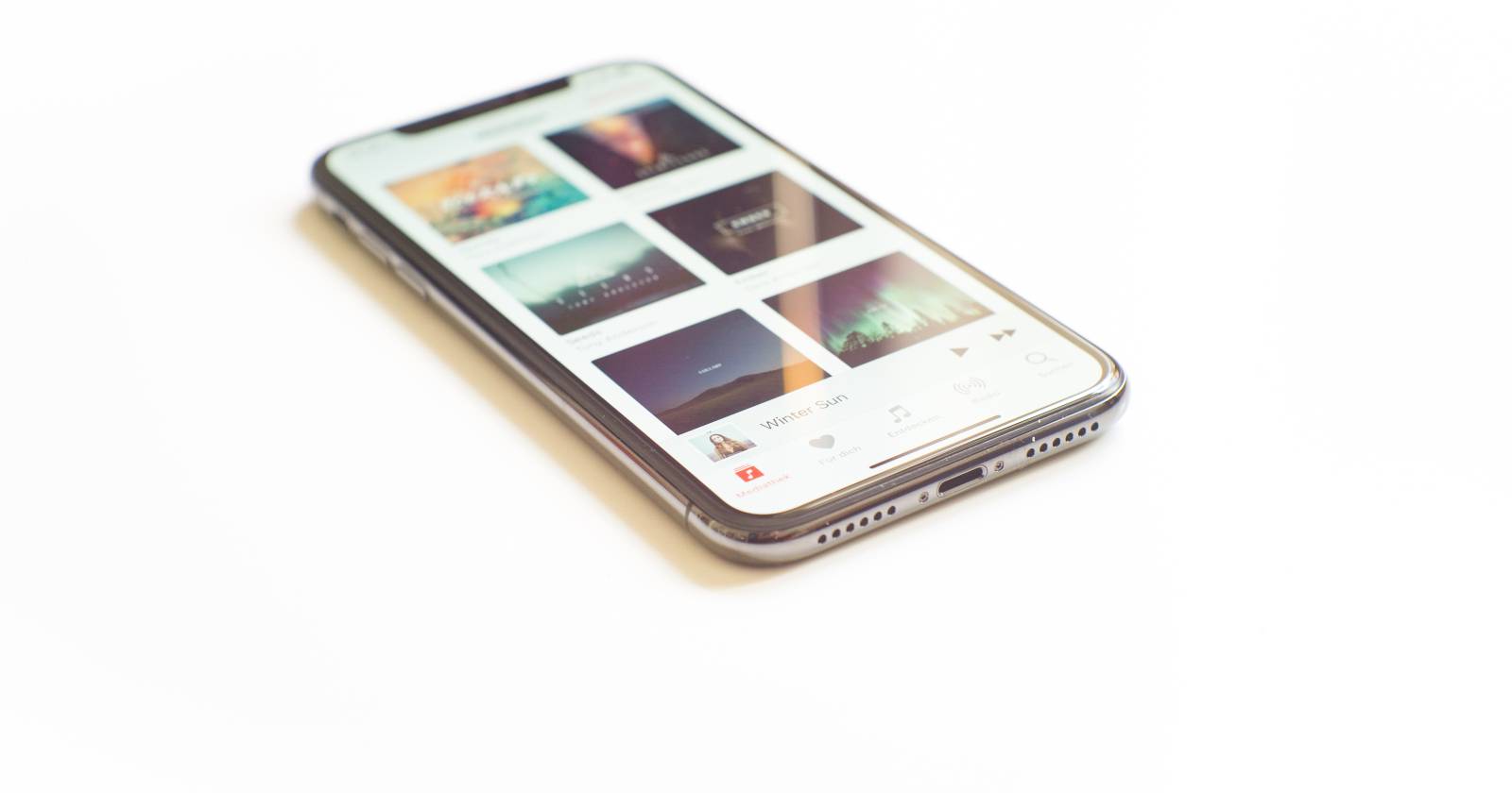 Серебристый iPhone X с открытым приложением Apple Music на экране