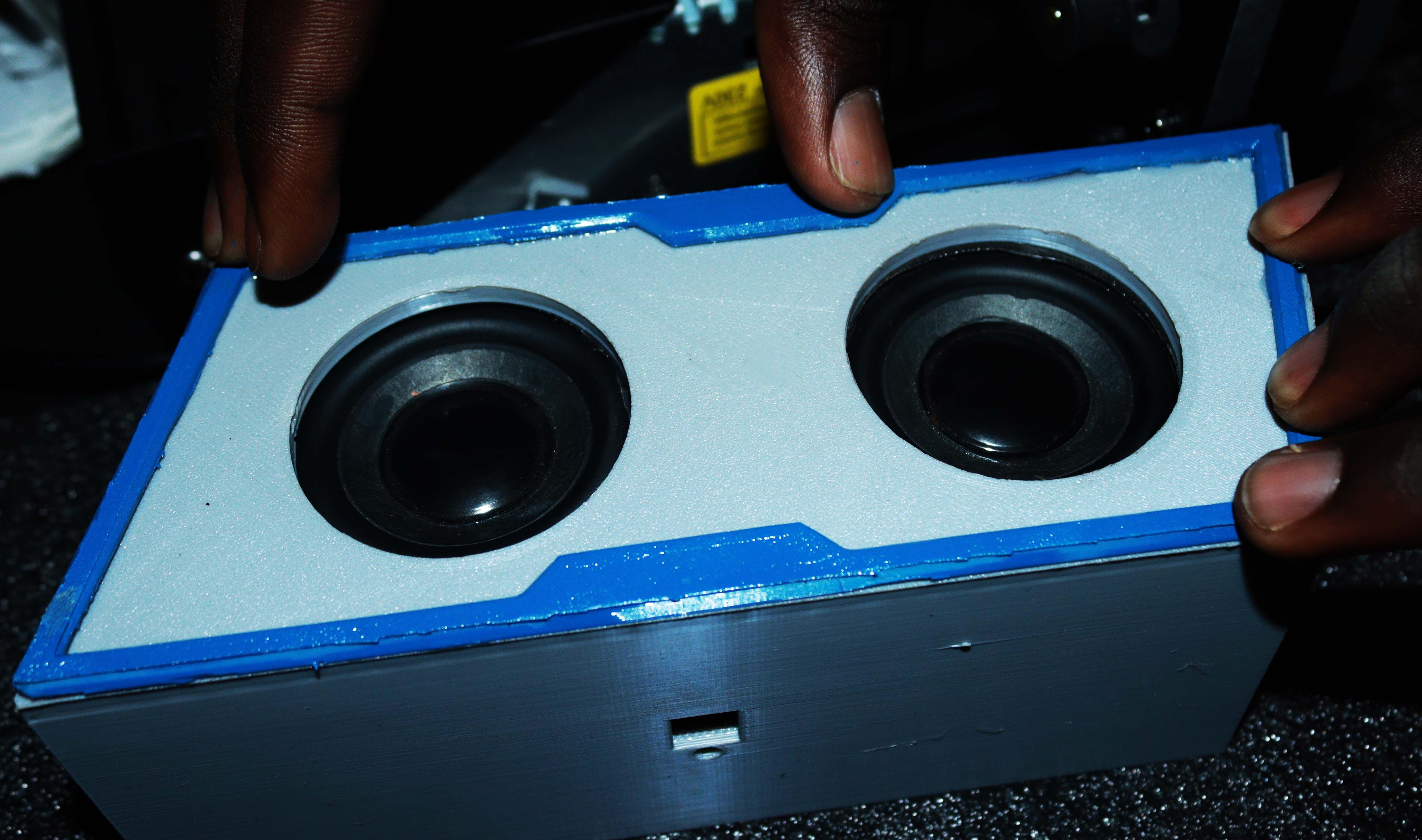 Руки держат белый Bluetooth-динамик с синими полосками