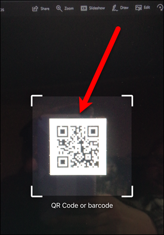 Камера iPhone направлена на QR‑код, внутри рамки с белыми уголками