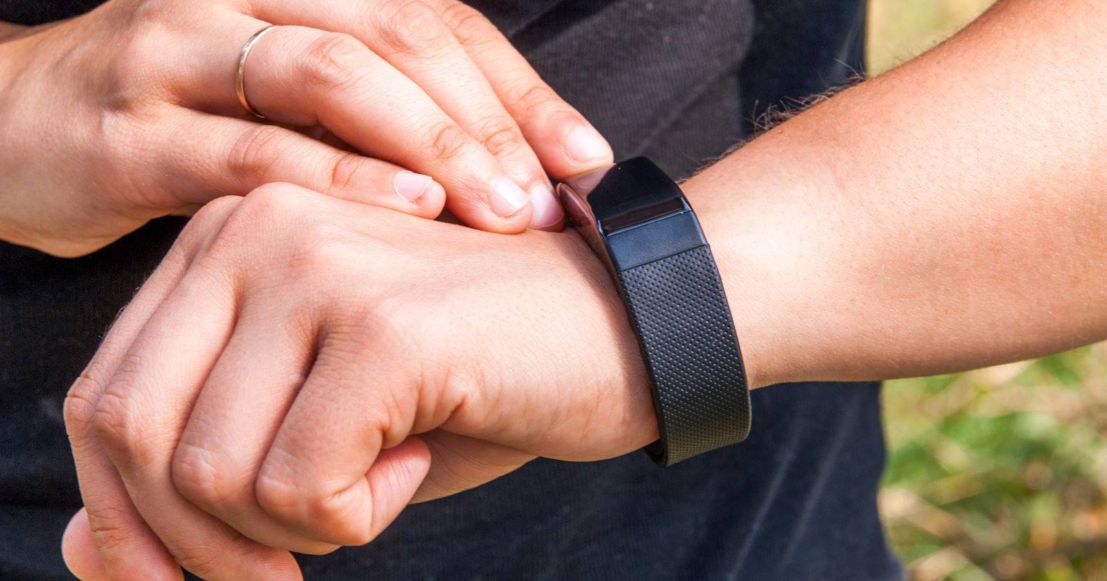 Фитнес-трекер Fitbit на запястье и интерфейс приложения на телефоне
