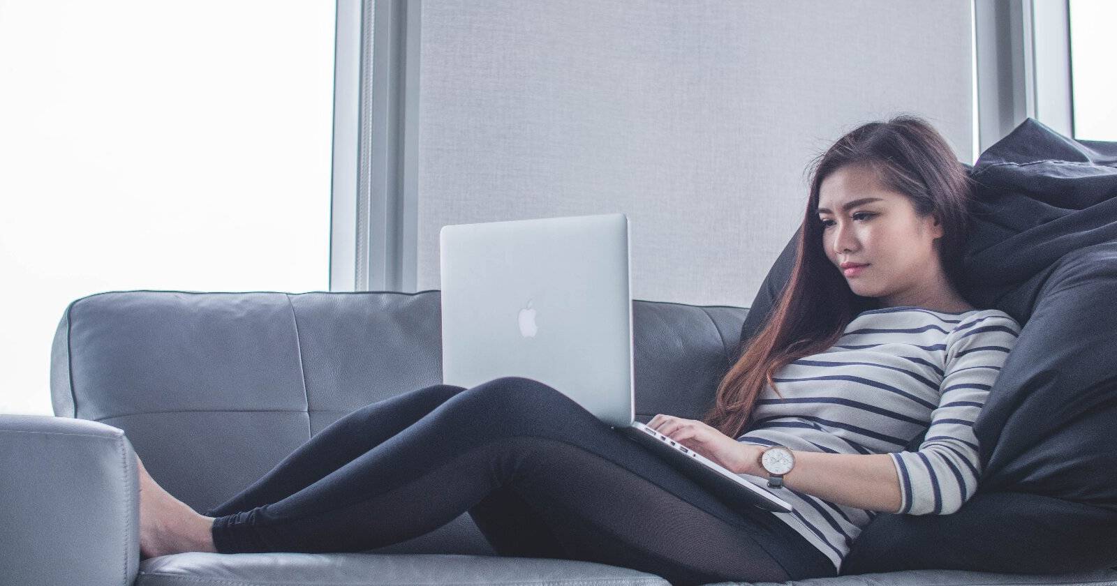 Женщина работает из дома с ноутбуком на диване