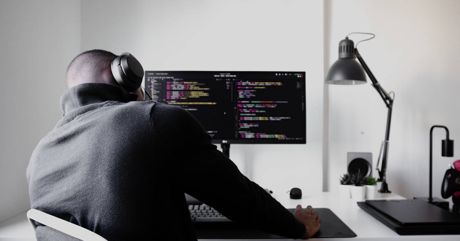 Мужчина в чёрной худи отвлекается за рабочим столом и откладывает дела