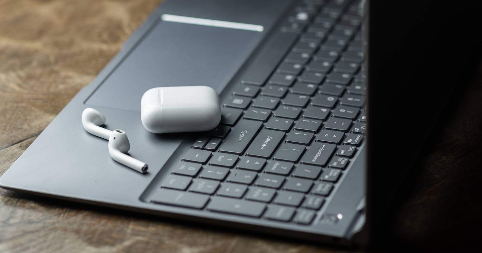 AirPods в зарядном футляре на клавиатуре ноутбука с Windows