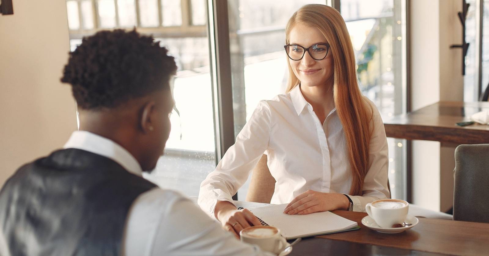 Женщина и мужчина сидят за столом напротив друг друга, готовые к беседе