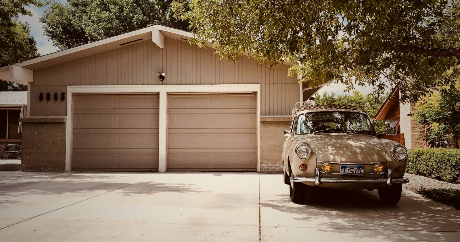 Коричневая гаражная дверь с старой машиной спереди