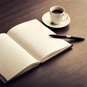 Книга на столе рядом с чашкой кофе и ноутбуком