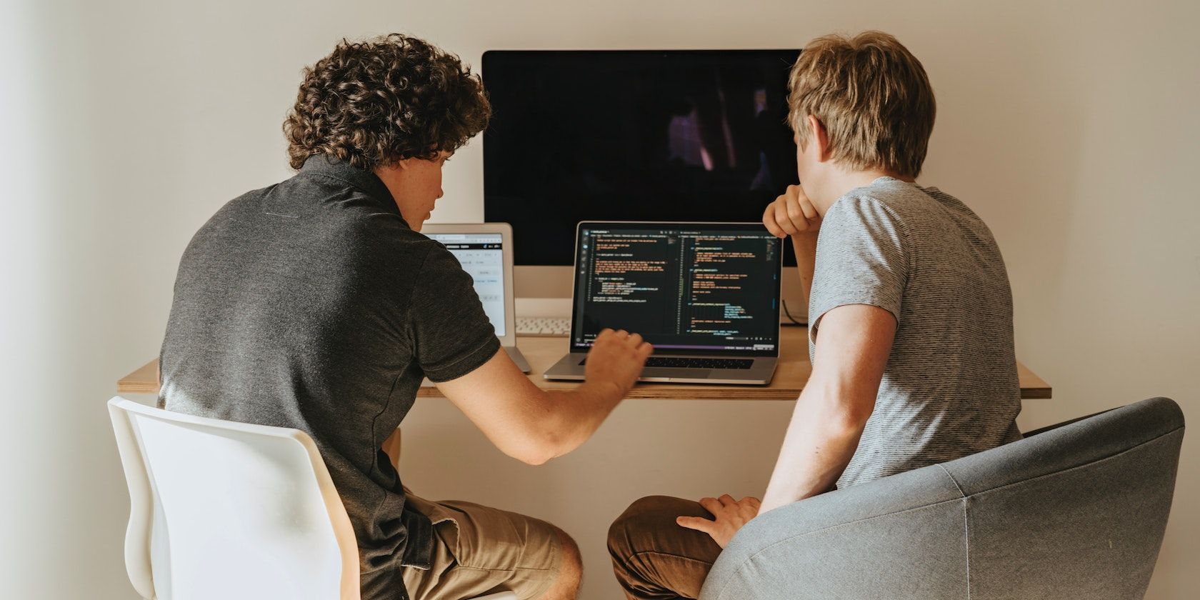 Два мужчины смотрят в экран ноутбука и обсуждают код