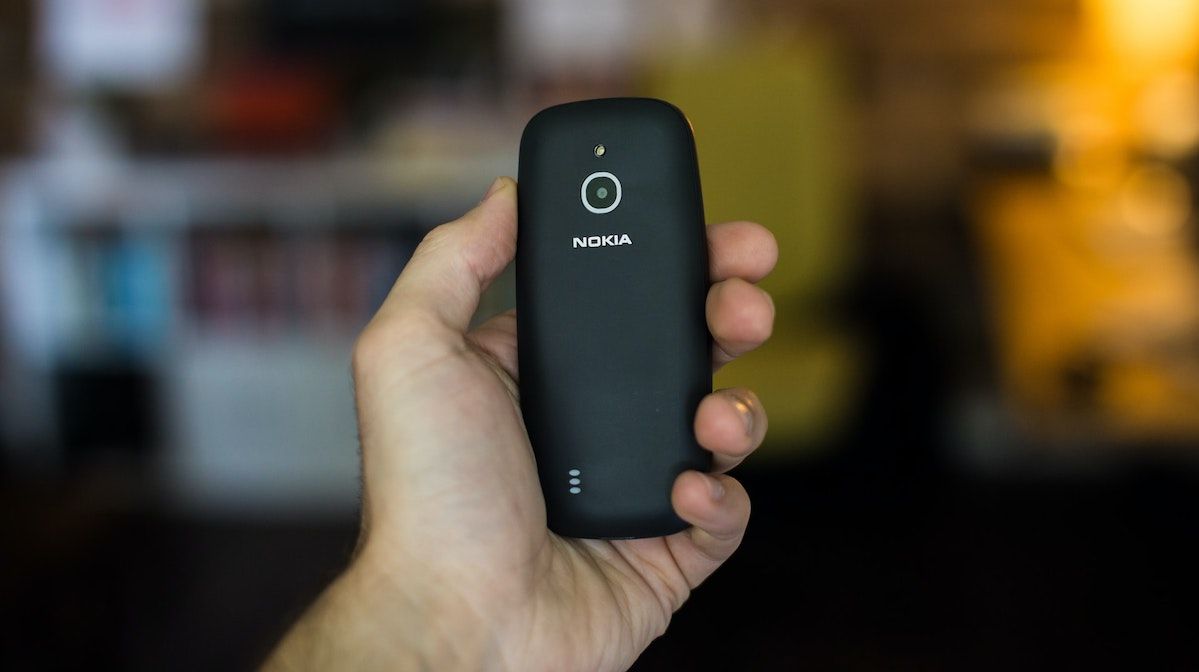 Рука держит классический телефон Nokia без функций смартфона