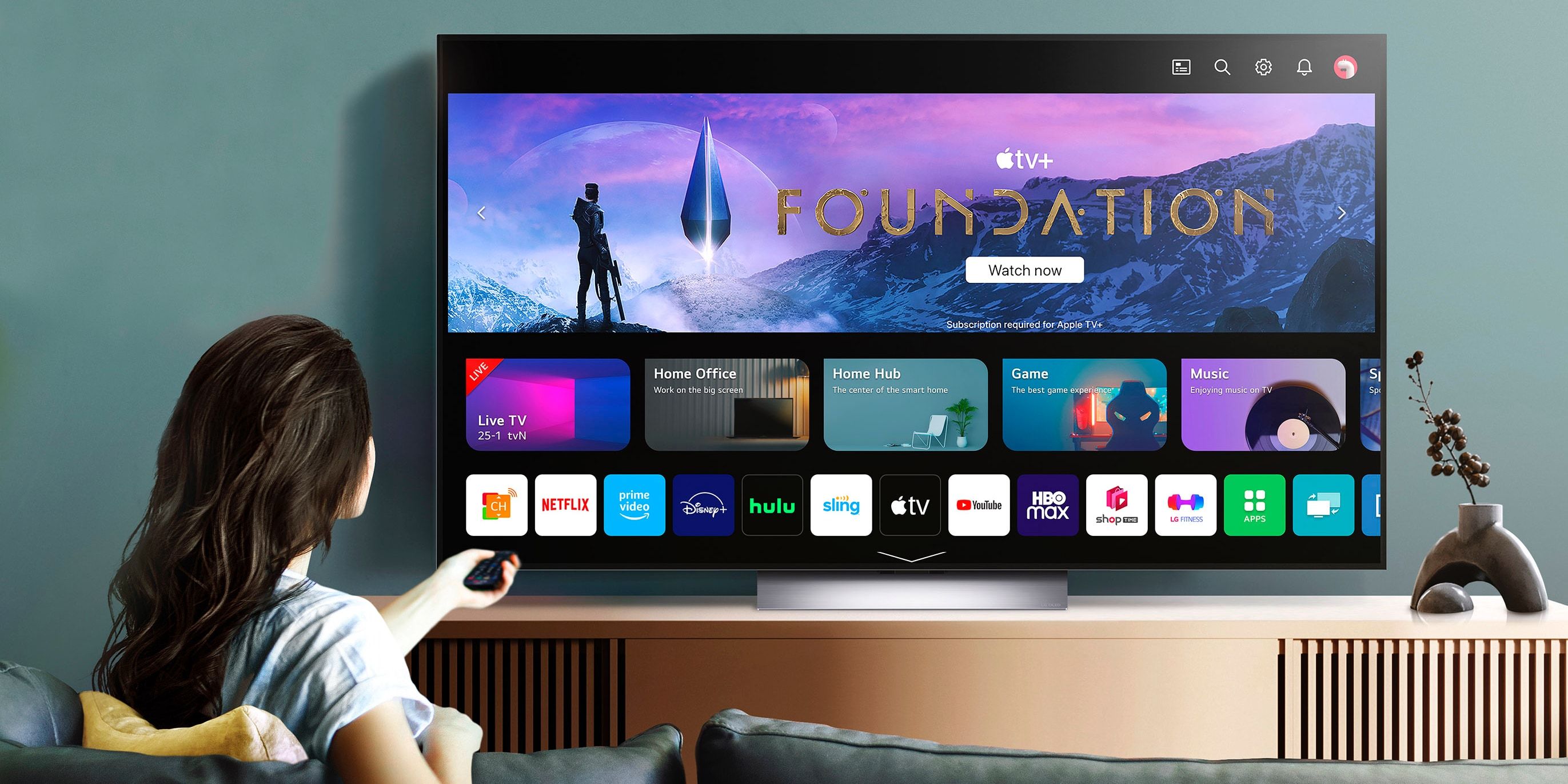 Человек на диване смотрит сериал Apple TV+ Foundation на OLED‑телевизоре LG.