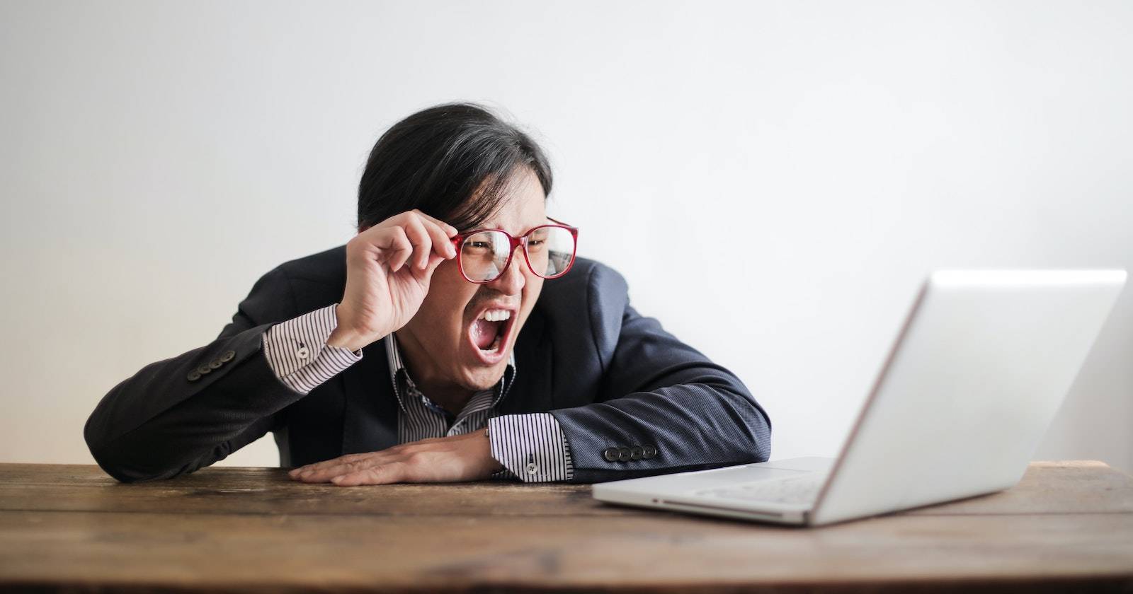 Человек кричит на ноутбук, стоящий на столе