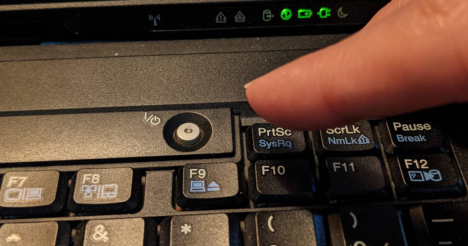 Пальцы над клавишей SysRq на клавиатуре ноутбука