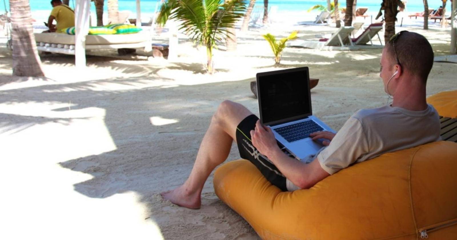 Человек работает за Mac на пляже