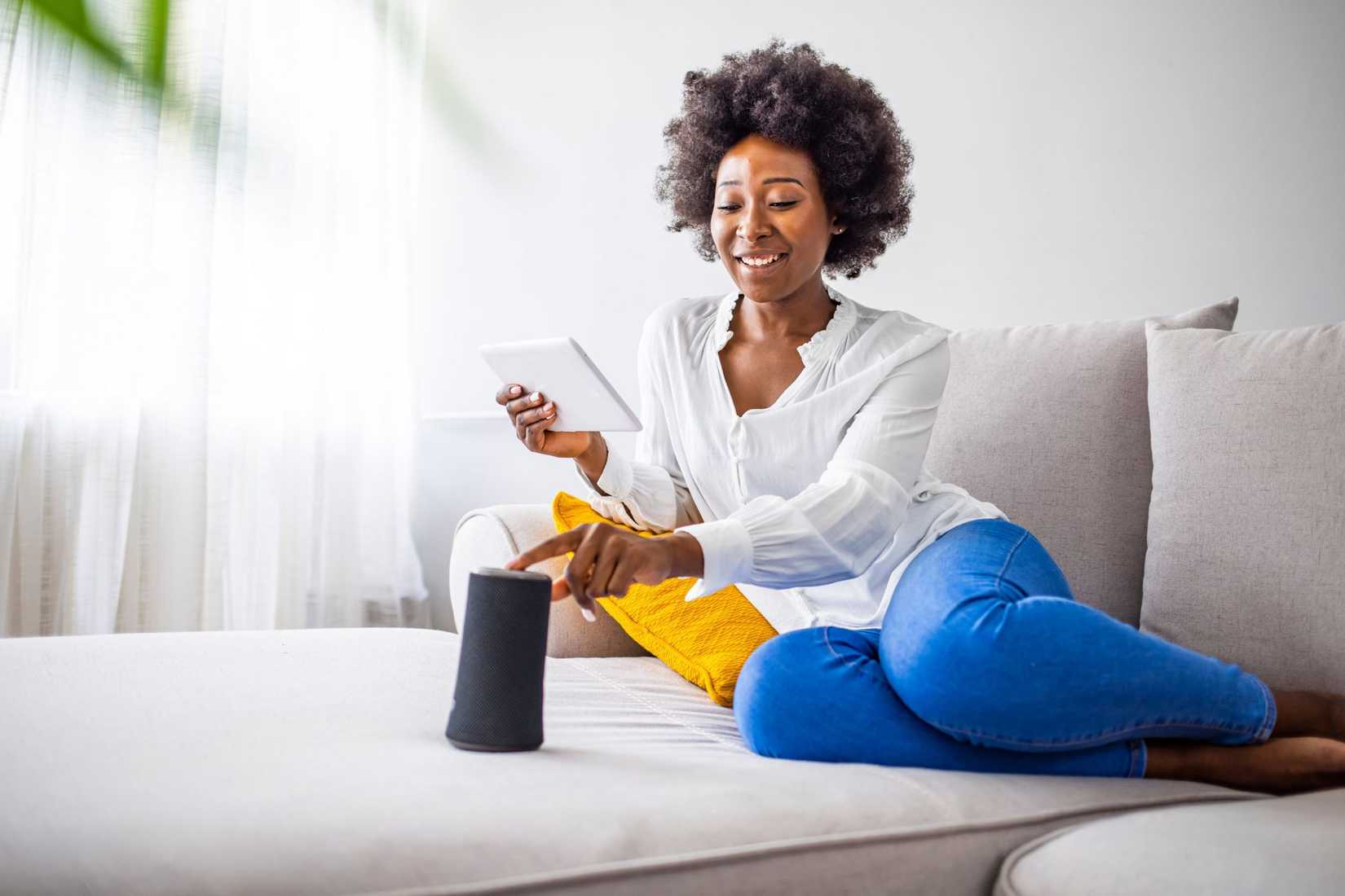 женщина использует умную колонку и планшет