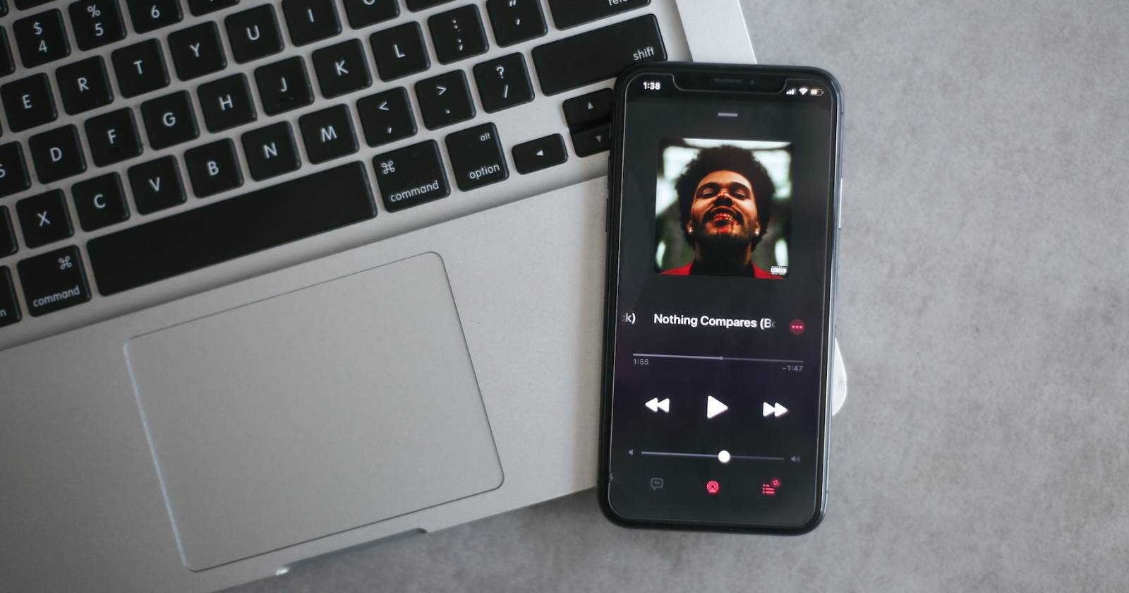 iPhone с открытым Apple Music на фоне MacBook