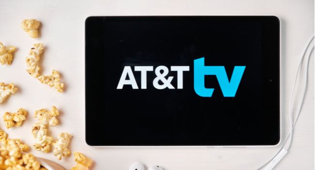 Логотип AT&T TV на планшете рядом с рассыпанным попкорном