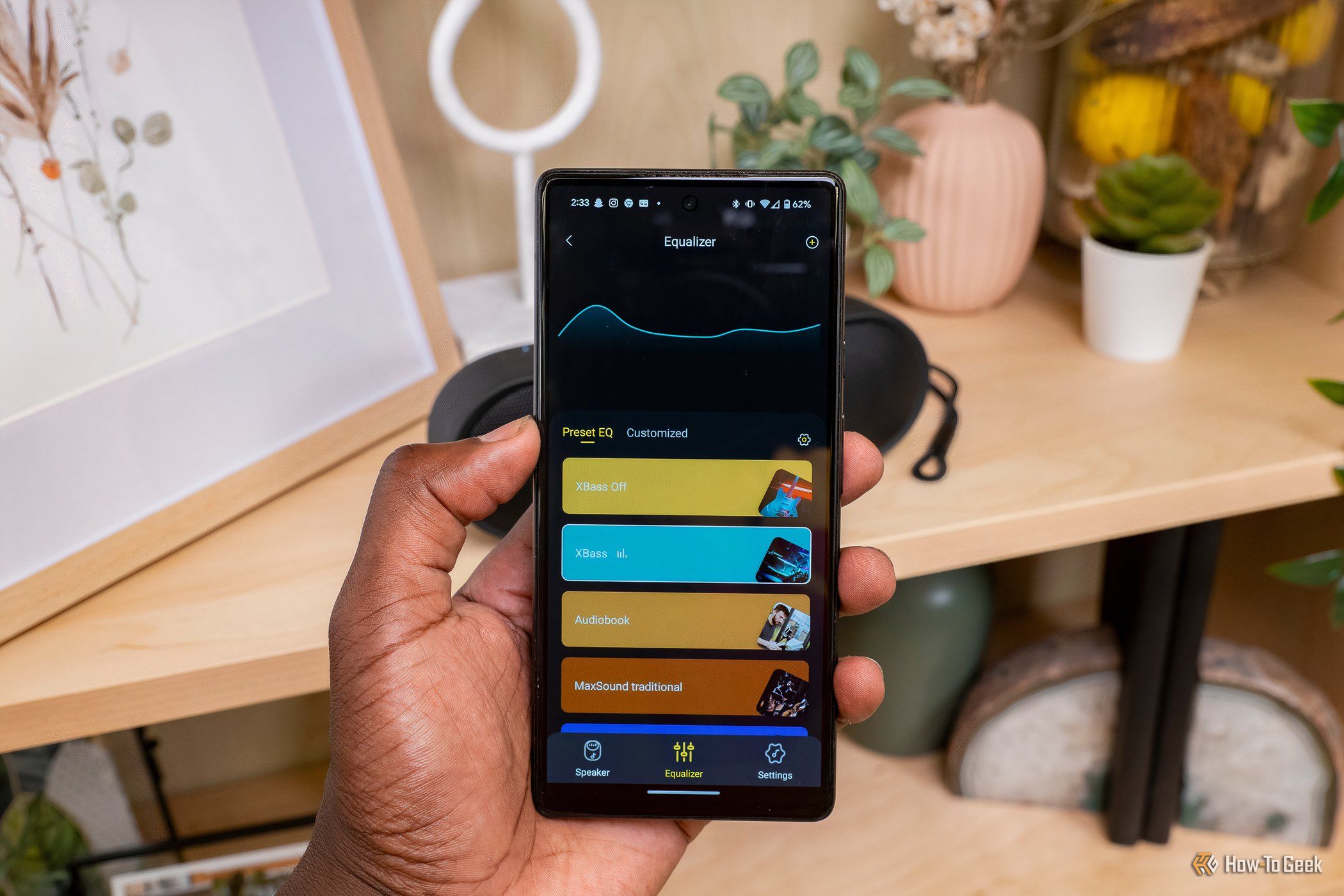 Рука держит смартфон с эквалайзером приложения Tribit.