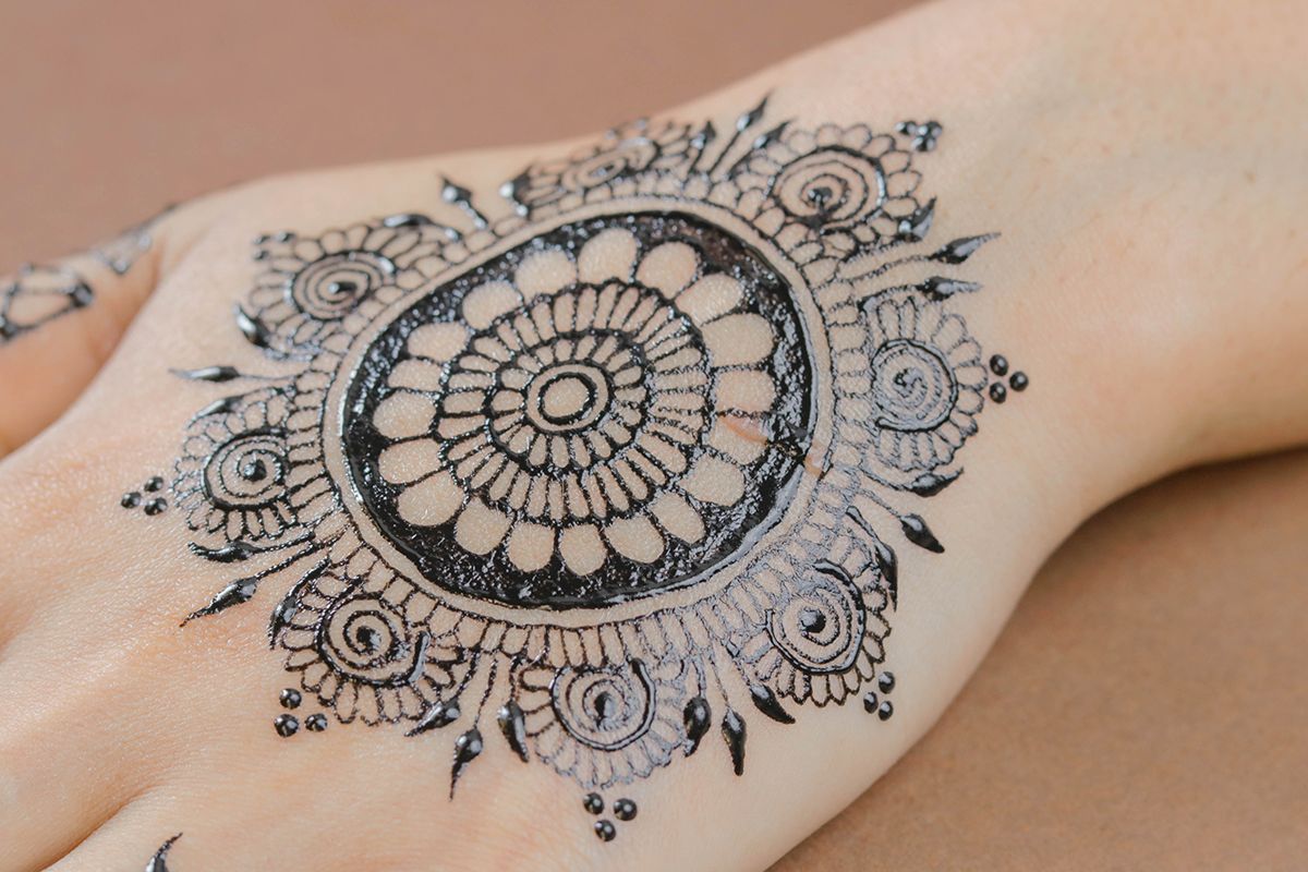 Mandala drawn in henna on the back of hand.