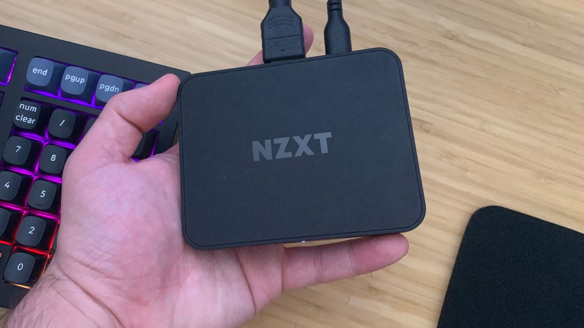 Карта захвата NZXT Signal 4K30 в руке над рабочим столом