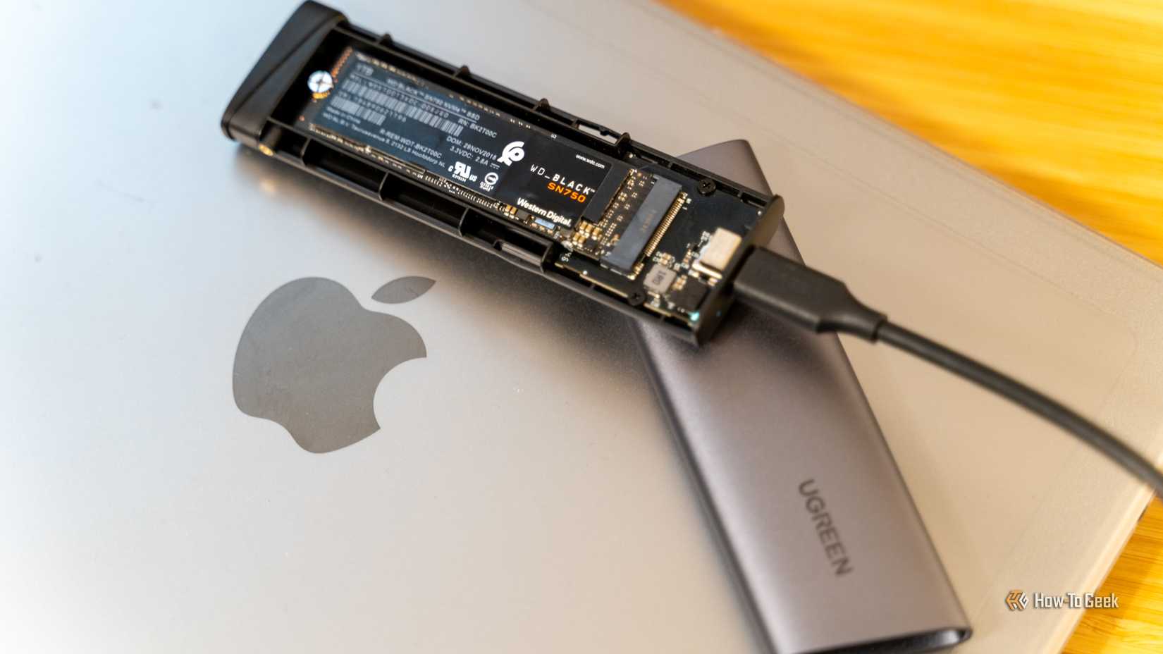 USB-корпус UGREEN с NVMe SSD внутри, лежащий на MacBook.