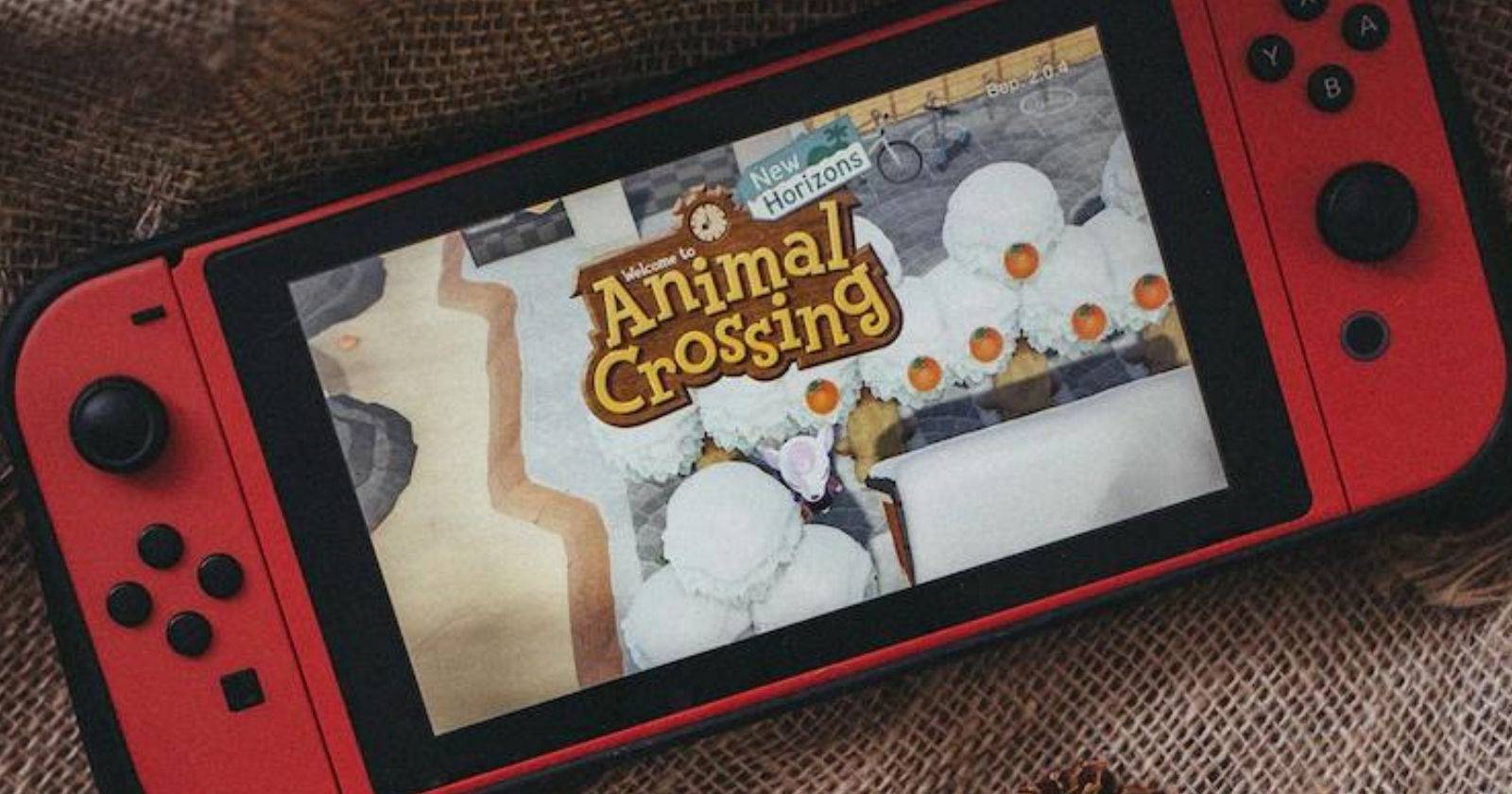 Красная консоль Nintendo Switch, на которой запущена Animal Crossing New Horizons, лежащая на ткани