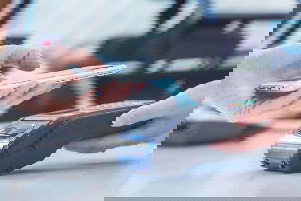 Человек подносит iPhone к терминалу оплаты.