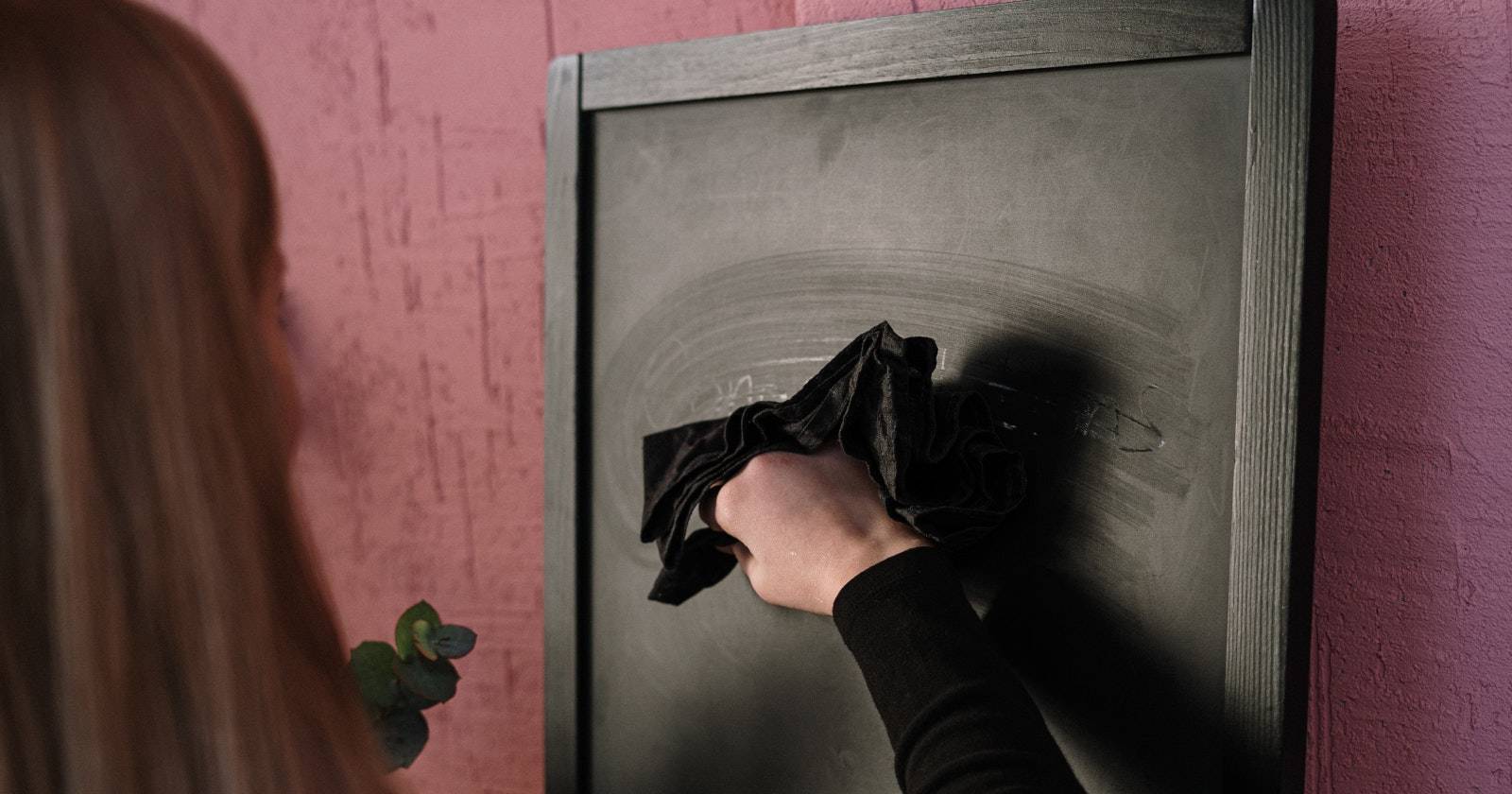 Женщина стирает мел с доски тканью