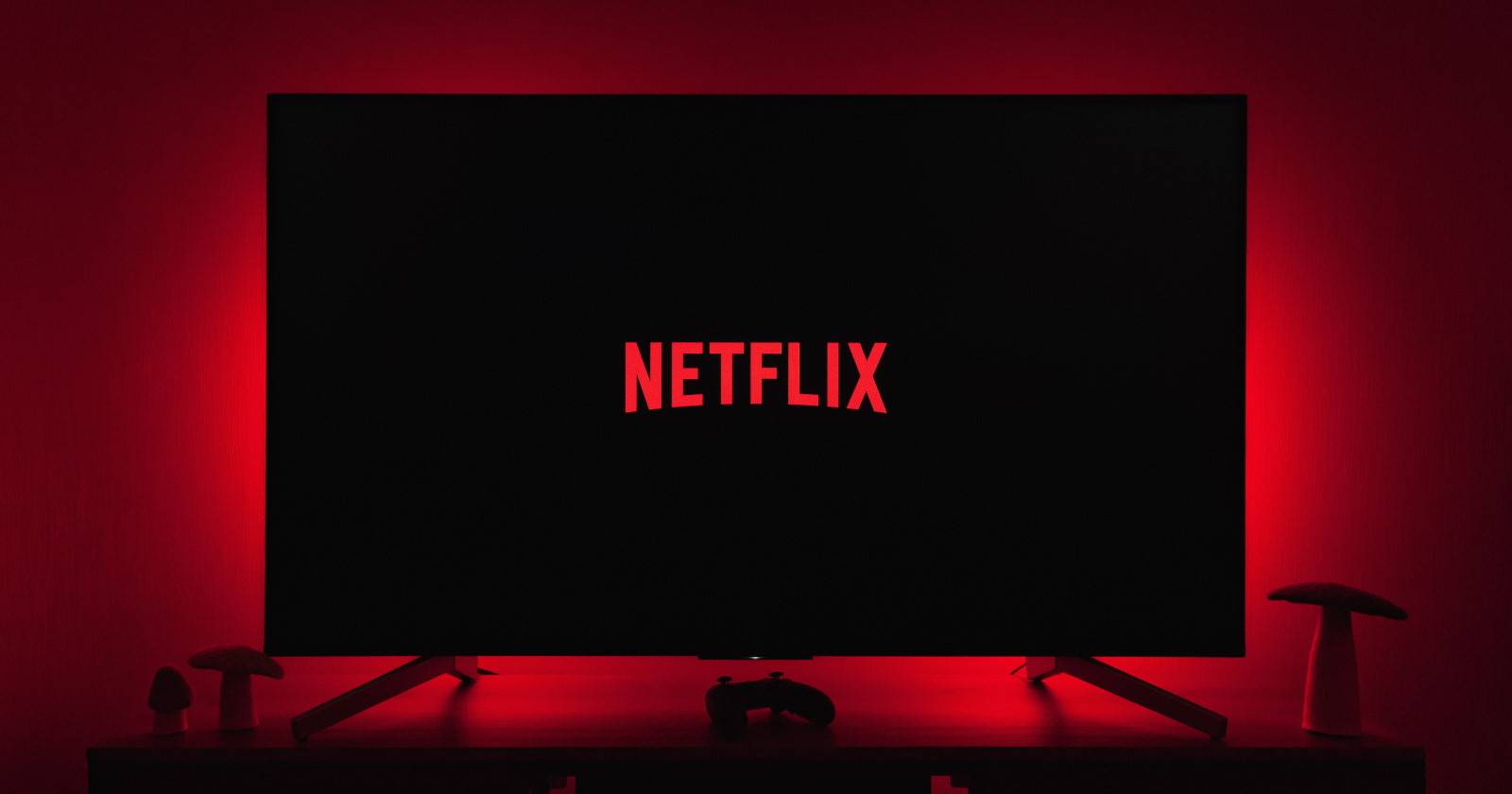 Netflix логотип на большом телевизоре в тёмной комнате с красной подсветкой