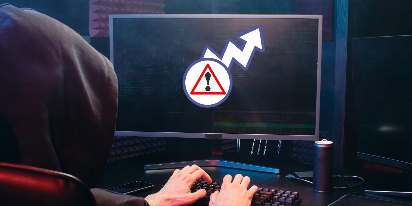 hooded person on computer with hazard symbol and arrow