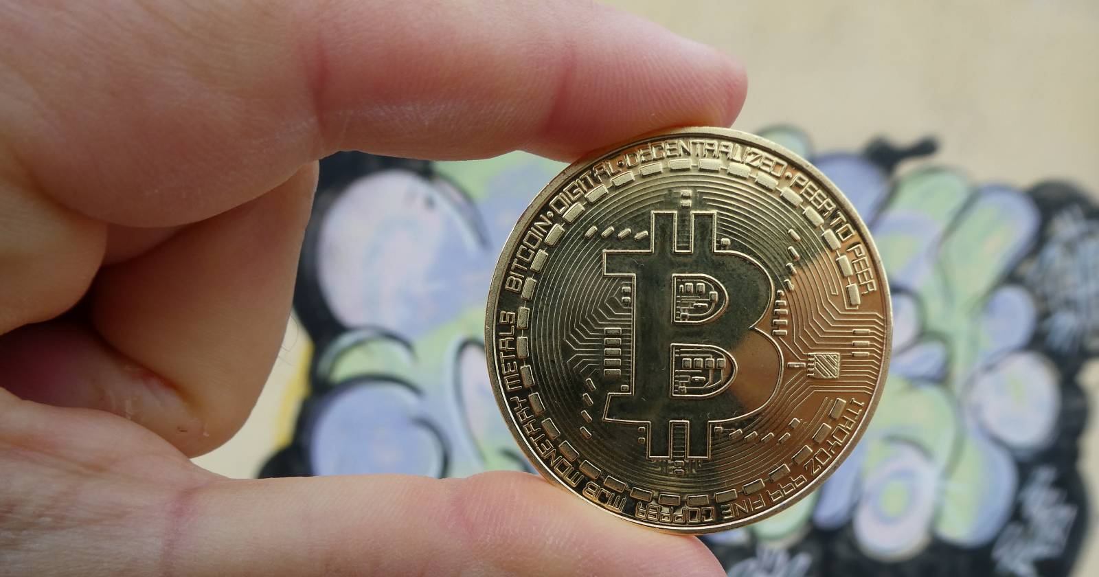 Рука держит монету биткоин на тёмном фоне