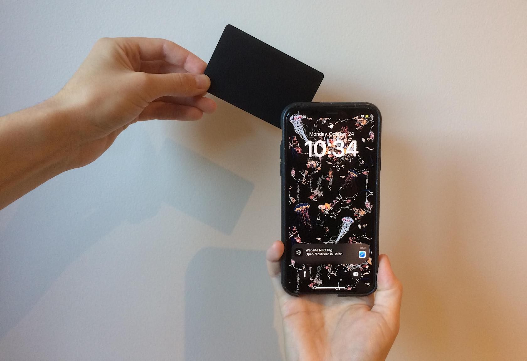 Рука подносит NFC‑карту к iPhone, который открывает ссылку в браузере.