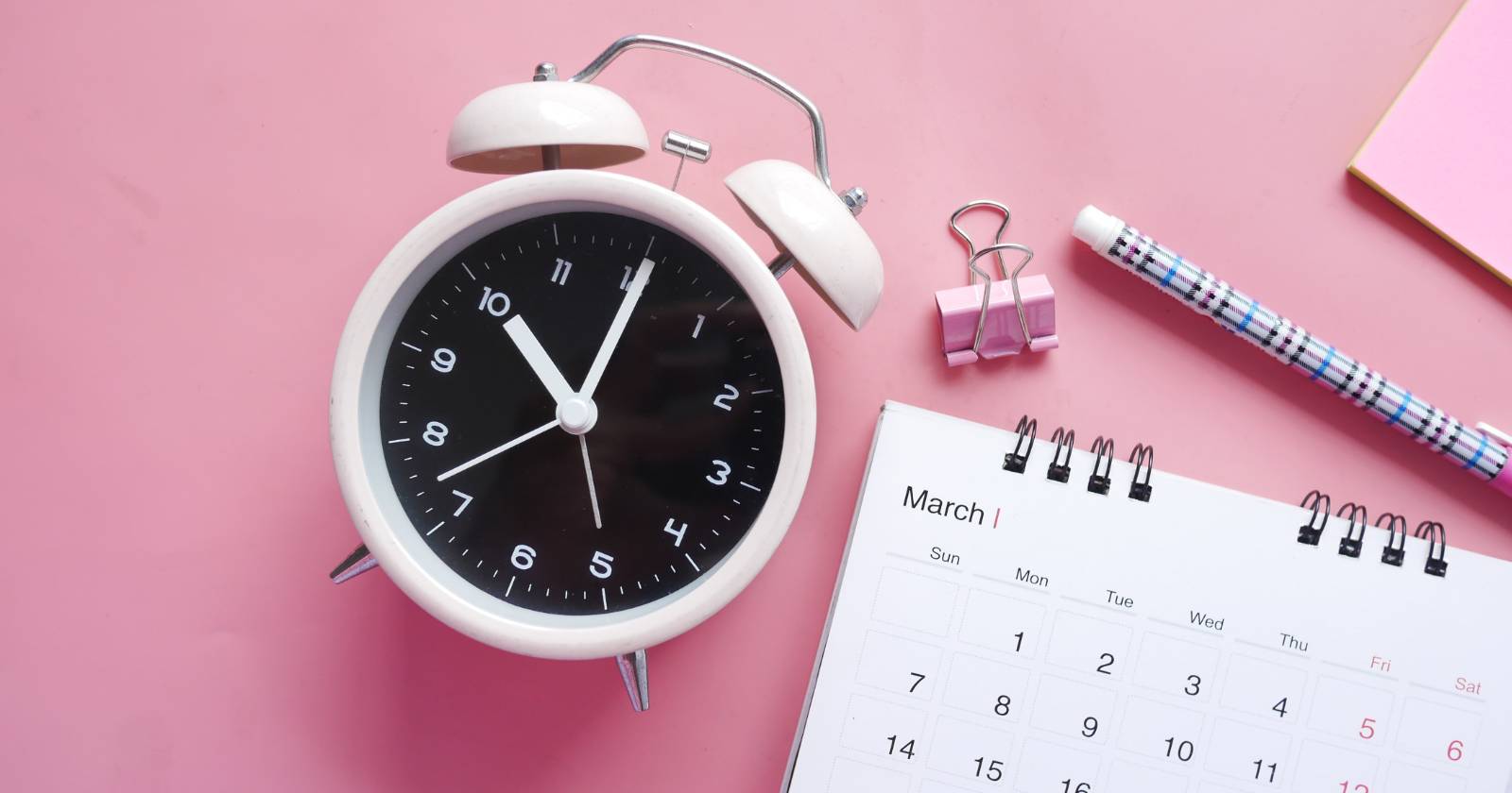 Часы и календарь рядом с канцелярскими принадлежностями
